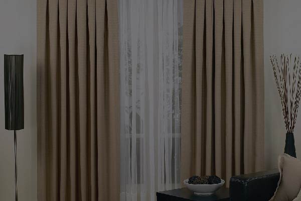 White pleated draperies behind brown pleated curtains
